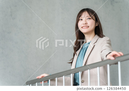 灰色背景辦公大樓裡微笑的年輕亞洲女商人 126384450