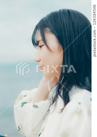 A young woman operating a smartphone with a calm sea in the background 126384506