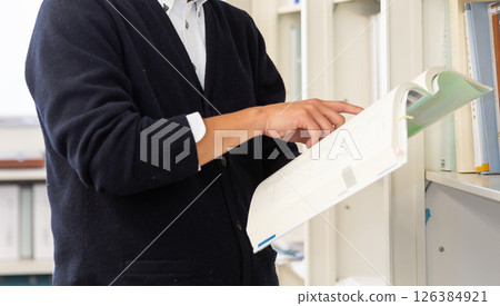 畫面中,一名男子的手正在辦公室圖書館打開一本書,並指向一份文件。 畫面中,一名男子的手正在辦公室圖書館打開一本書,並指向一份文件。 126384921