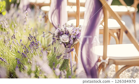 Aisle with wooden chairs and purple lavender floral decorations at an outdoor wedding ceremony in the garden 126384970