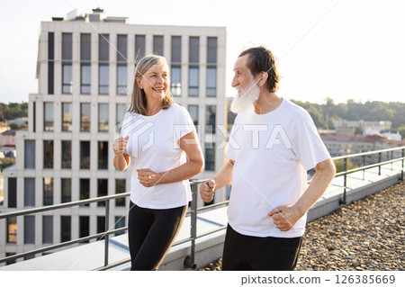 Active senior man and woman jogging outdoors on rooftop, showcasing healthy lifestyle and fitness Active senior man and woman jogging outdoors on rooftop, showcasing healthy lifestyle and fitness 126385669