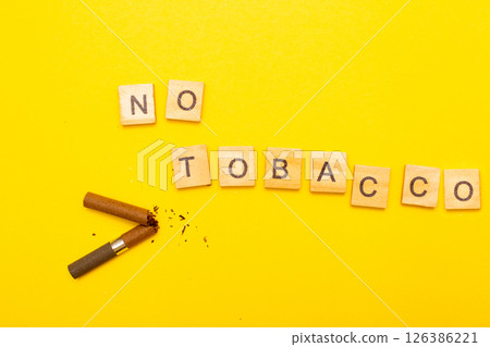 Top view of broken cigarette with the word no tabaco on a yellow background closeup Top view of broken cigarette with the word no tabaco on a yellow background closeup 126386221