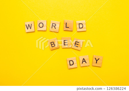 Top view of World bee day text on yellow background Top view of World bee day text on yellow background 126386224