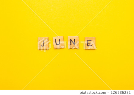 Top view of word June month made by wooden cubes with letters on a yellow bright background Top view of word June month made by wooden cubes with letters on a yellow bright background 126386281