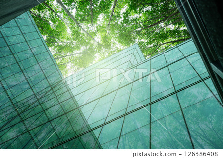 Eco-friendly building in modern city. Sustainable glass office building with trees for reducing carbon dioxide. Office building with green environment. Corporate building reduce CO2. Net zero emission 126386408