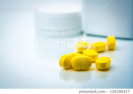 Yellow prescription tablets pill with pharmaceutical container blurred in background. Modern medication development for patient care. Healthcare treatment concept. Pharmaceutical industry product. 126386427