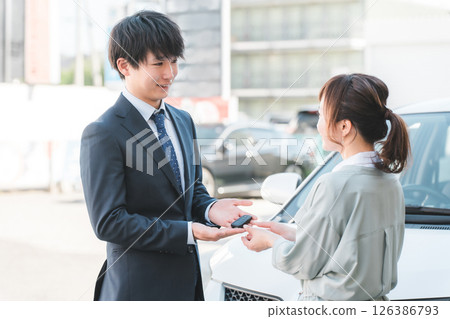 Young salesman handing over car keys to female customer, male salesman 126386793