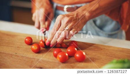 Cooking, woman and hands cut tomatoes in kitchen for dinner salad, organic recipe and vegetarian food. Wood board, person and vegetable ingredients for meal preparation, lunch cuisine and nutrition Cooking, woman and hands cut tomatoes in kitchen for dinner salad, organic recipe and vegetarian food. Wood board, person and vegetable ingredients for meal preparation, lunch cuisine and nutrition 126387227