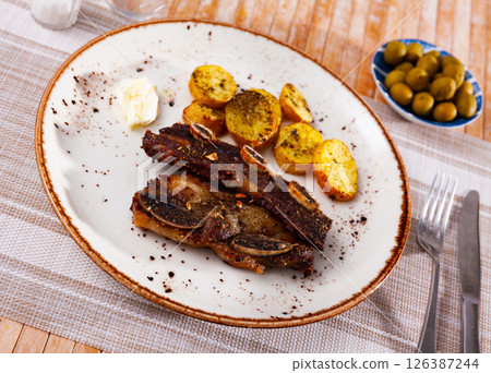 Spanish cuisine churrasco de ternera, spare ribs with potatoes on white ceramic plate Spanish cuisine churrasco de ternera, spare ribs with potatoes on white ceramic plate 126387244
