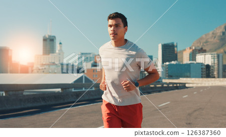 Man, fitness and running in city street for workout, cardio exercise or outdoor training. Active, male person or runner with lens flare on road for physical activity, health or wellness in urban town 126387360