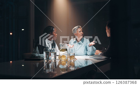 Documents, teamwork and business people at night meeting for overtime, planning or office. Creative startup, collaboration and man and woman working on project, proposal and brainstorming in dark 126387368