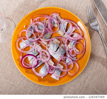 Raw herring with onions served on platter 126387369