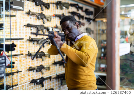 Portrait of african american man in gun shop showing rifle Portrait of african american man in gun shop showing rifle 126387400