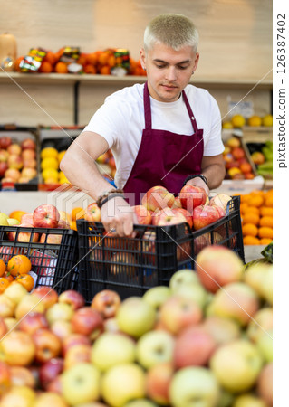 Supermarket employee carries box of ripe apples 126387402