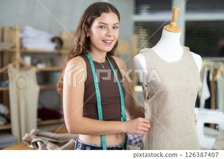 Dressmaker constructing custom dress on mannequin in sewing workshop Dressmaker constructing custom dress on mannequin in sewing workshop 126387407
