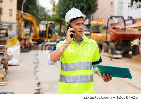Engineer having telephone conversation in construction area Engineer having telephone conversation in construction area 126387420