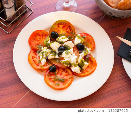 Caprese salad of mozzarella and tomatoes with pesto and olives 126387435
