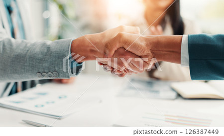 Shaking hands, paperwork and business people in office with meeting for deal, agreement or partnership. Corporate, documents and finance manager with client for handshake on investment contract. Shaking hands, paperwork and business people in office with meeting for deal, agreement or partnership. Corporate, documents and finance manager with client for handshake on investment contract. 126387449