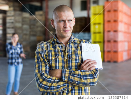 Confident male manager with documents inside large warehouse 126387514