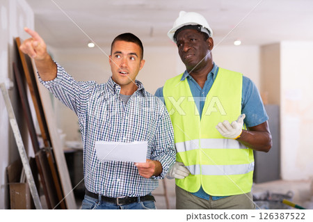 Owner of apartment discusses with foreman where and what to repair Owner of apartment discusses with foreman where and what to repair 126387522
