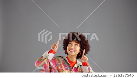 Fashion, happy woman and pointing up for advertising, mockup info and discount news. African person, marketing and show space for retro style, sales promotion or coming soon on gray studio background Fashion, happy woman and pointing up for advertising, mockup info and discount news. African person, marketing and show space for retro style, sales promotion or coming soon on gray studio background 126387540