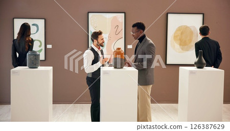 Smile, business people and talking with negotiation for exhibition, event and gallery opening with curator. Team, men and art director with client for museum, discussion and creativity in office 126387629