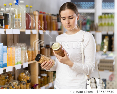 Woman carefully chooses canned beans and lentils 126387630
