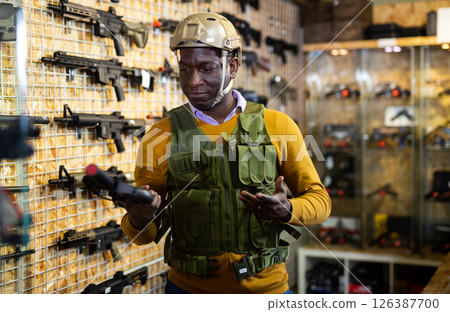 African american man in army uniform with weapon in military shop African american man in army uniform with weapon in military shop 126387700