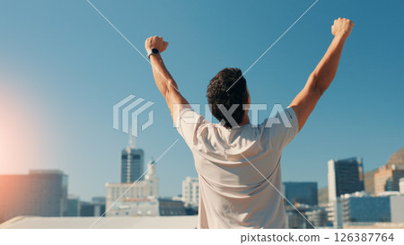 Man, back and fitness with fist pump in city for conquer, achievement or workout success. Active, male person or runner with relief for exercise goals, accomplishment or winning in an urban town 126387764