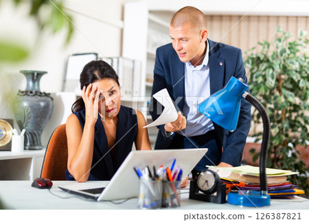 Frustrated female entrepreneur sitting at office desk with angry partner Frustrated female entrepreneur sitting at office desk with angry partner 126387821