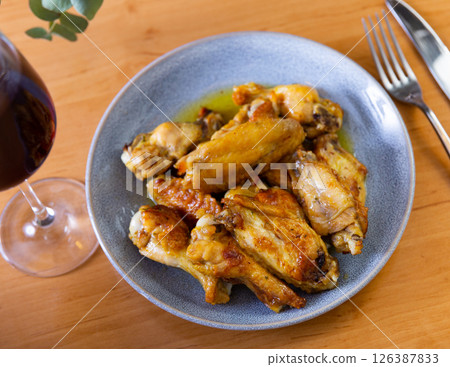 On plate is hearty snack - portion of fried chicken wings with crispy crust, poured with thick barbecue sauce On plate is hearty snack - portion of fried chicken wings with crispy crust, poured with thick barbecue sauce 126387833