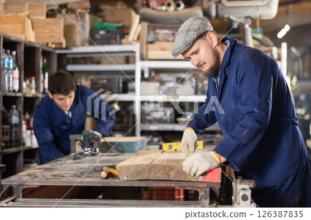 Young man measuring wooden board with tape measure Young man measuring wooden board with tape measure 126387835