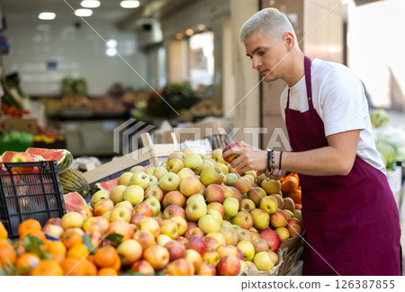 Guy shop seller puts apple goods on display case 126387855