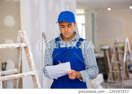 Young foreman checks the completed construction work and signs the documents 126387857