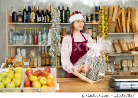 Store clerk in Santa hat offering Christmas gift basket 126387887