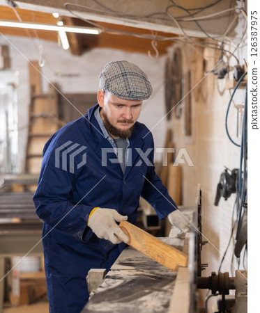 Young man working with wooden board on workbench 126387975