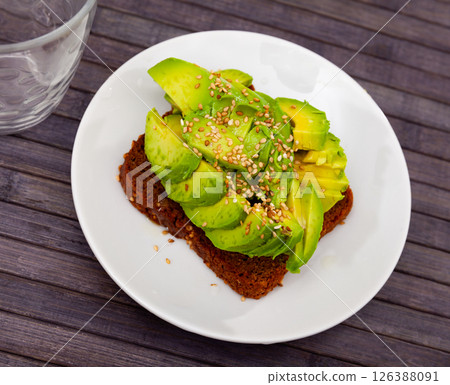 Sandwich with black bread, sliced avocado and sesame 126388091