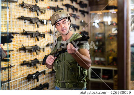 Guy in military equipment with weapon in army shop Guy in military equipment with weapon in army shop 126388099