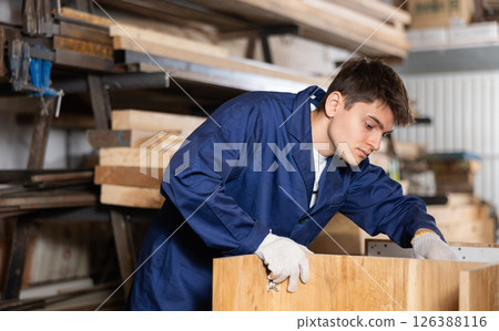 Young worker assembles a wooden table in furniture factory. Work process 126388116