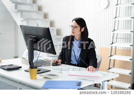 A woman working while spreading out construction-related documents A woman working while spreading out construction-related documents 126388260