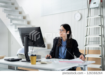 一名婦女在工作時攤開與建築相關的文件 126388264