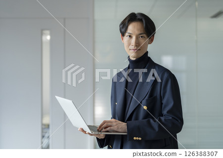 A businessman in his 30s holding a laptop computer, looking at the camera A businessman in his 30s holding a laptop computer, looking at the camera 126388307