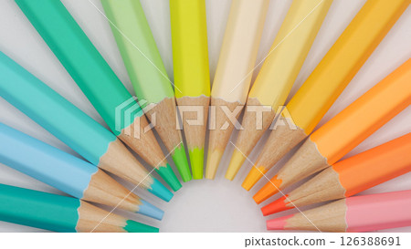 a semicircular fan of colored pencils, focusing on cool greens, aquas, and blues on the left, transitioning into yellows and warm oranges on the right 126388691