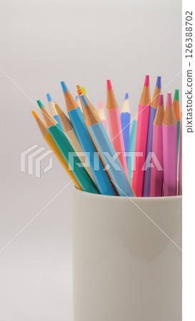 The colored pencils arranged in a white cup evoke a sense of potential, creativity waiting to be expressed. 126388702