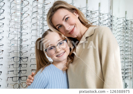 Mom and daughter in optic shop looking positive after choosing new eyeglasses 126388975