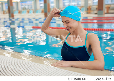 Pretty young woman in blue swimming cap looking enjoyed 126389126