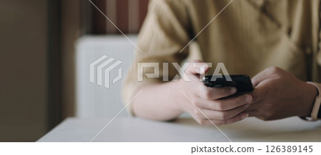 Mockup image of a woman holding mobile phone with blank black screen in cafe 126389145