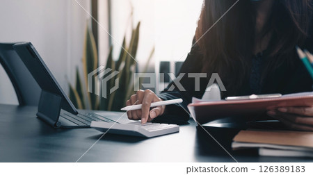 Close up Business woman using calculator and laptop for do math finance on wooden desk in office and business working background, tax, accounting, statistics and analytic research concept 126389183