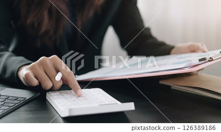 Close up Business woman using calculator and laptop for do math finance on wooden desk in office and business working background, tax, accounting, statistics and analytic research concept Close up Business woman using calculator and laptop for do math finance on wooden desk in office and business working background, tax, accounting, statistics and analytic research concept 126389186