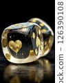Two translucent resin dice featuring gold hearts and dots sit atop a smooth black surface, showcased in soft lighting. The delicate designs attract attention in their elegant arrangement. 126390108
